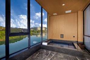 A modern spa room with large windows, a wooden ceiling, and a view of a lake and buildings. - Guangdong Hot Spring Hotel  (Guangzhou)