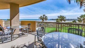 A balcony with a glass table and chairs, overlooking a beach and a pier. - Margate Penthouse Myrtle Beach (Myrtle Beach)