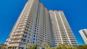 A tall, curved high-rise building with multiple balconies and a clear blue sky in the background. - Margate Penthouse Myrtle Beach (Myrtle Beach)