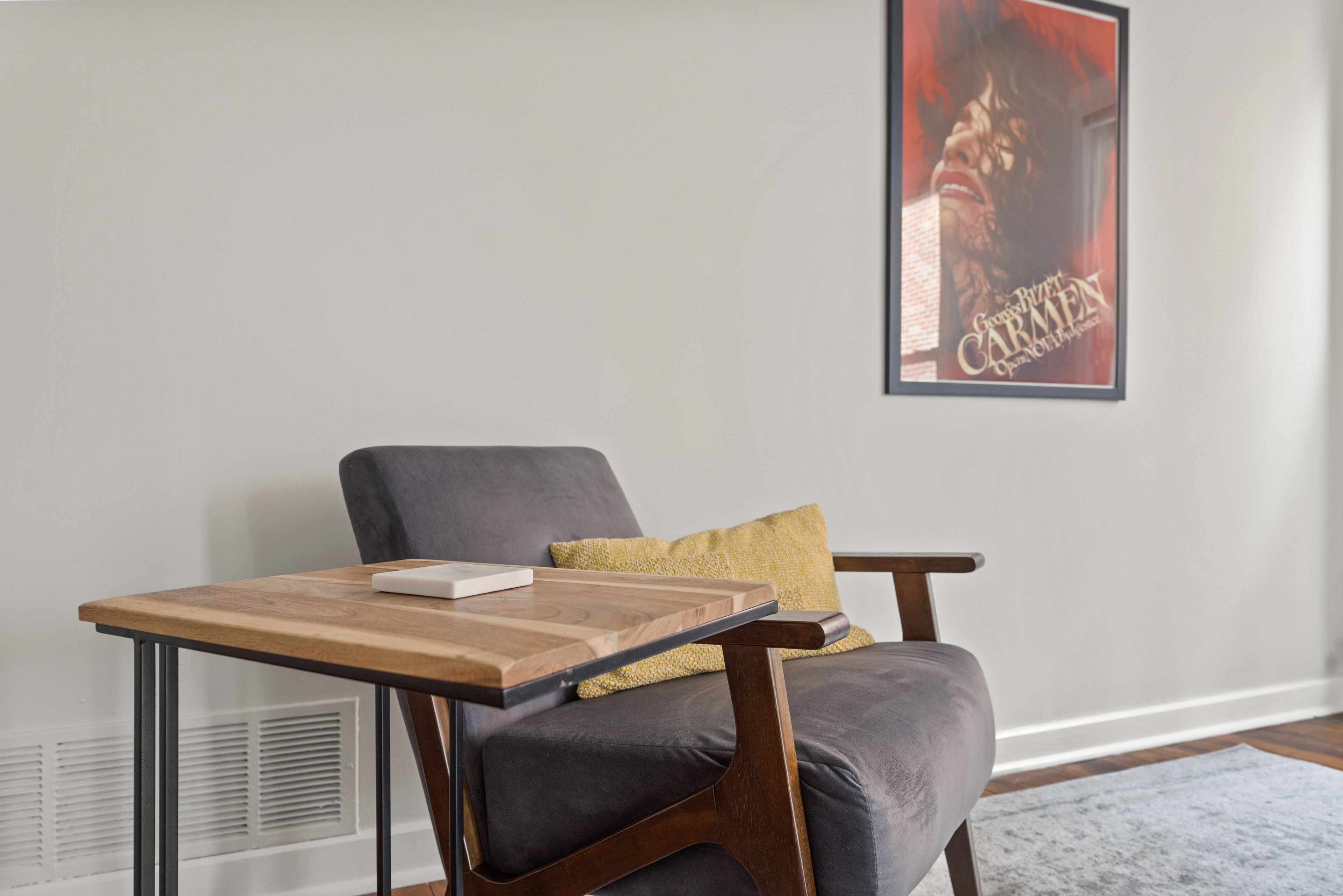A modern living room with a grey sofa, a wooden coffee table, and a poster on the wall.