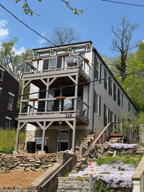 A multi-story building with a balcony, stone steps, and a 'No Stopping Parking Any Time' sign.