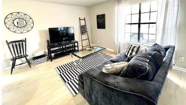 Ein Wohnzimmer mit einer Couch, einem Fernseher und einem Deckenventilator.