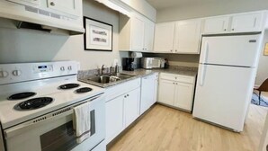 A kitchen with white cabinets, a stainless steel stove, a microwave, and a refrigerator. - Live like a local in our cozy, clean home! (Fayetteville)