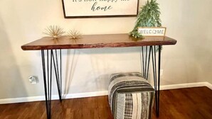 A wooden console table with a 'WELCOME' sign, a small potted plant, and a decorative item on the wall.