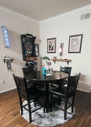 Enjoy meals in this dining area with a round table and four chairs, featuring a wall-mounted dartboard and artwork.