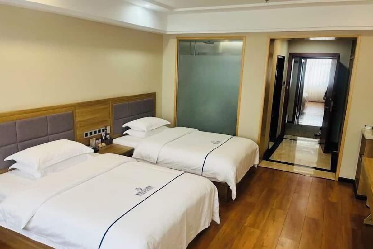 Une chambre d’hôtel avec deux lits, une tête de lit en bois, une table de chevet et un miroir.