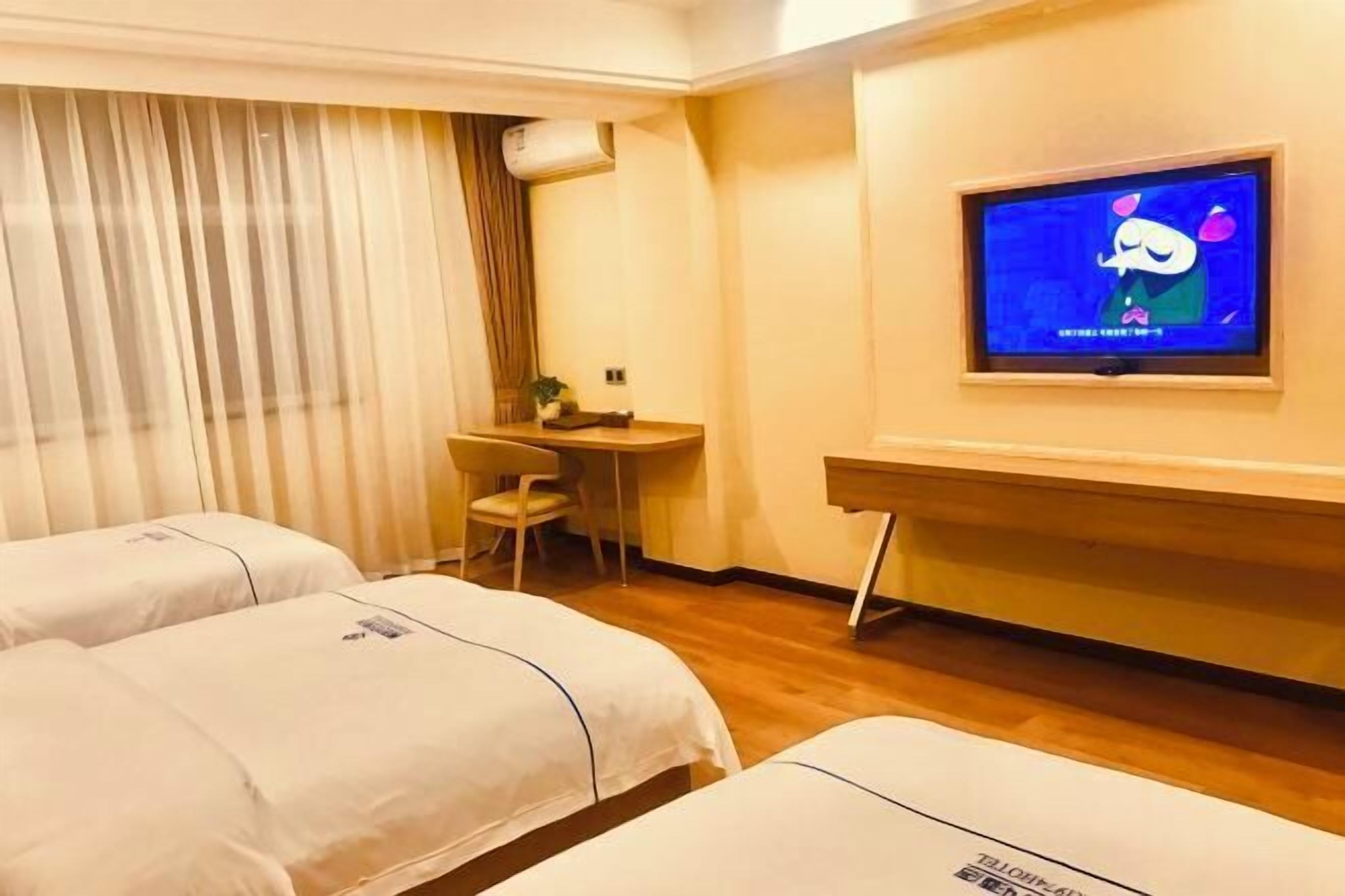 A hotel room with two beds, a desk, a chair, and a television on the wall.