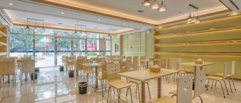 A spacious indoor area with tables and chairs arranged for dining, large windows allowing natural light, and a clean, modern design.