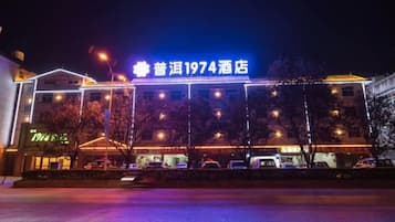 A hotel with a prominent sign, a covered entrance, and a parking lot.