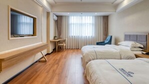 Habitación de hotel con dos camas, un escritorio, una silla, un televisor y una ventana con cortinas.