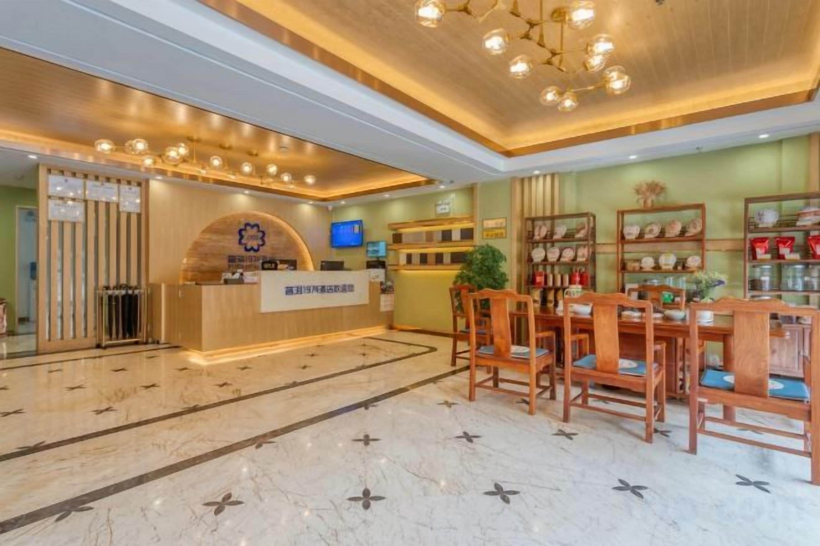 A hotel reception area with a reception desk, seating area, and a television screen.