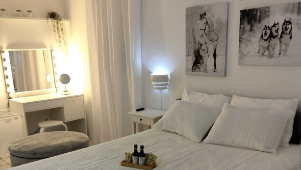 A neatly arranged bedroom with a bed, bedside tables, a vanity with a mirror, and artwork on the walls. - One of a kind! Apartment with everything. (Toa Baja)