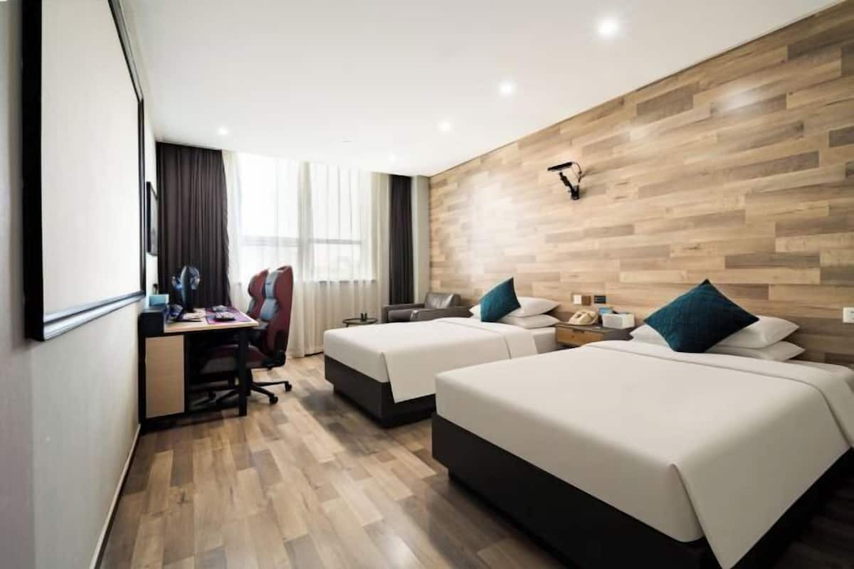 Ein Hotelzimmer mit zwei Betten, einem Schreibtisch, einem Stuhl und einem großen Fenster.