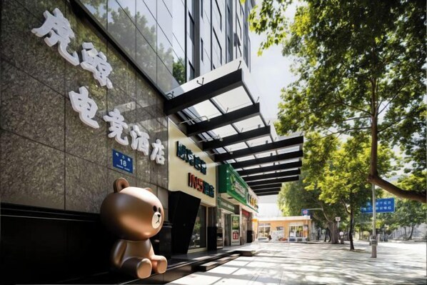 Un edificio con una gran escultura de oso en el exterior, un letrero con caracteres chinos y un paseo techado.