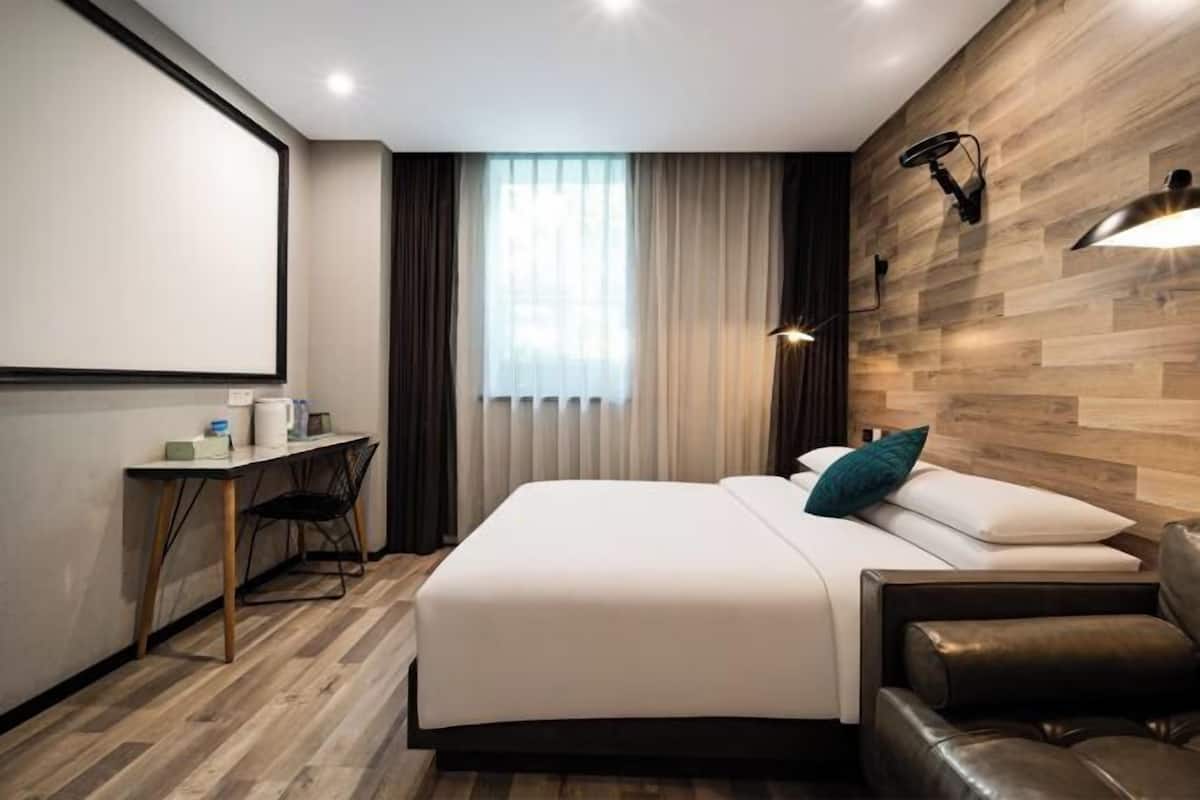 Ein modernes Hotelzimmer mit einem Bett, einem Schreibtisch, einem Stuhl und einem Ledersofa.