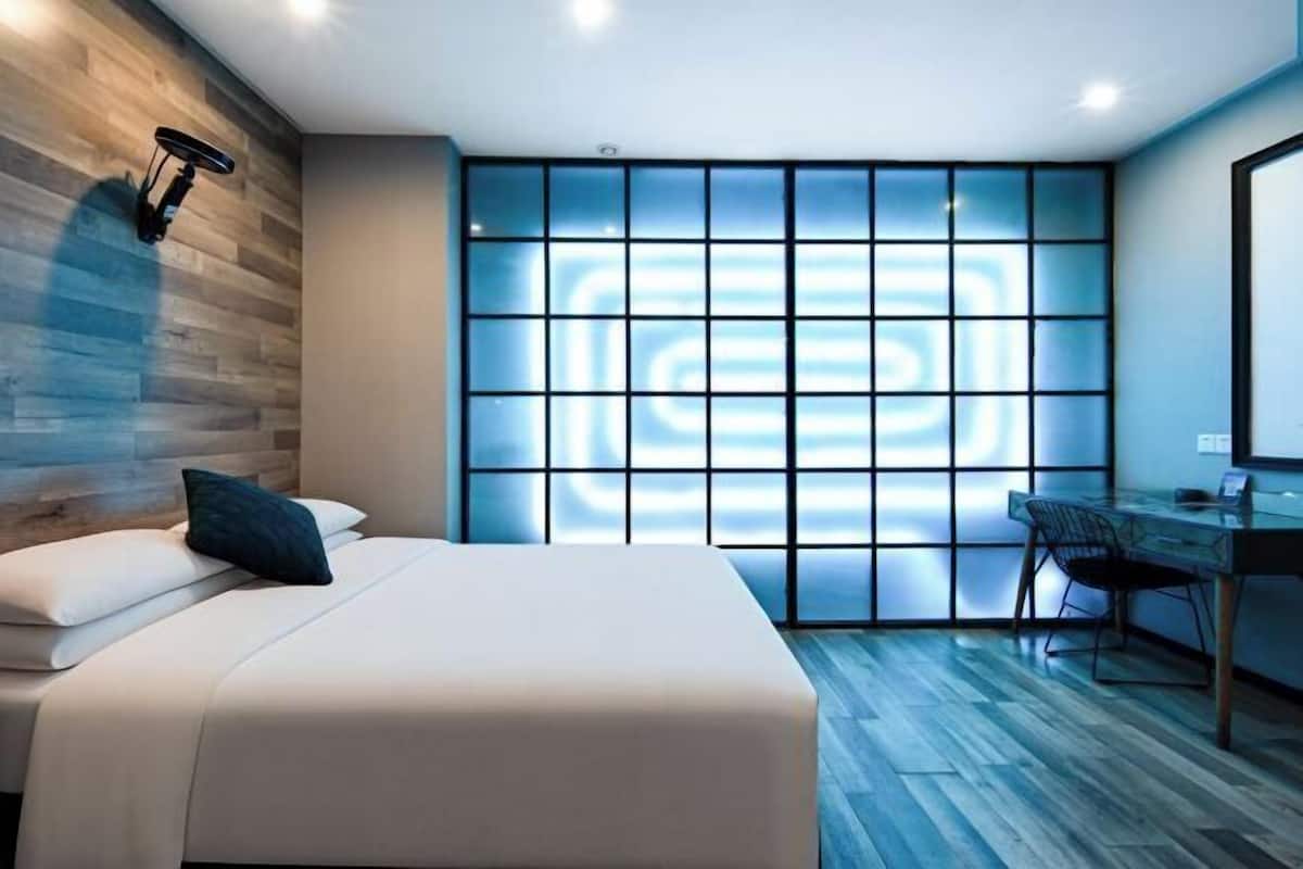 Ein modernes Schlafzimmer mit einem Bett, einem Schreibtisch und einem großen Fenster mit geometrischem Muster.