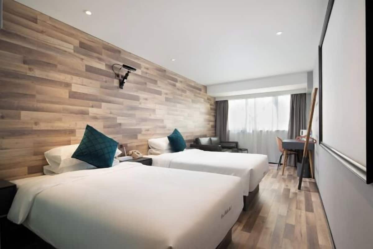 Ein Hotelzimmer mit zwei Betten, einer Holzwand, einem Schreibtisch und einem Sessel.