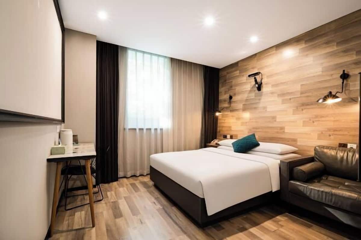 Ein modernes Hotelzimmer mit Bett, Schreibtisch, einer Ledersofa und einer Wand als Holzdekor.