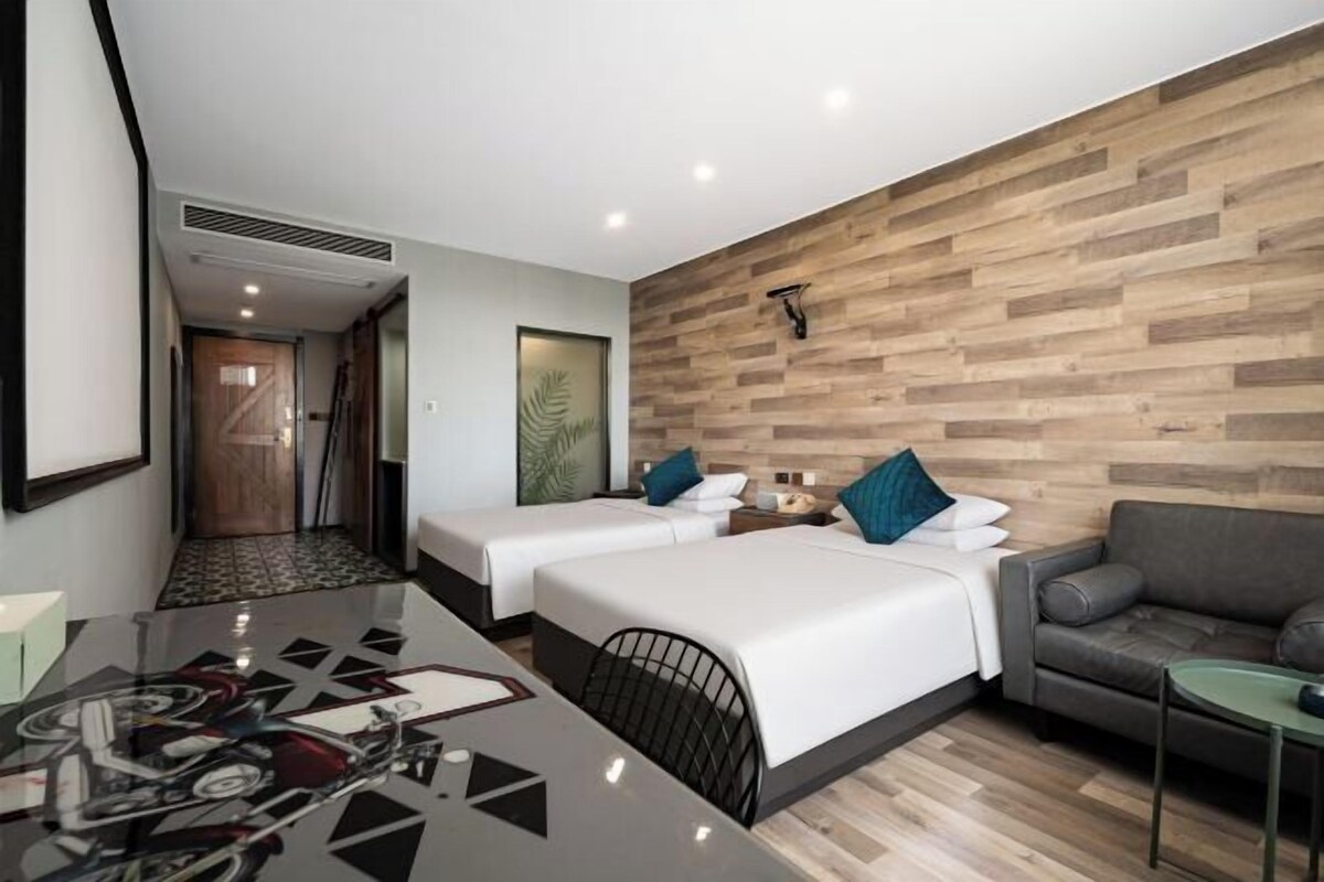 Una habitación de hotel con dos camas, un sofá, una mesita y un escritorio con una silla.
