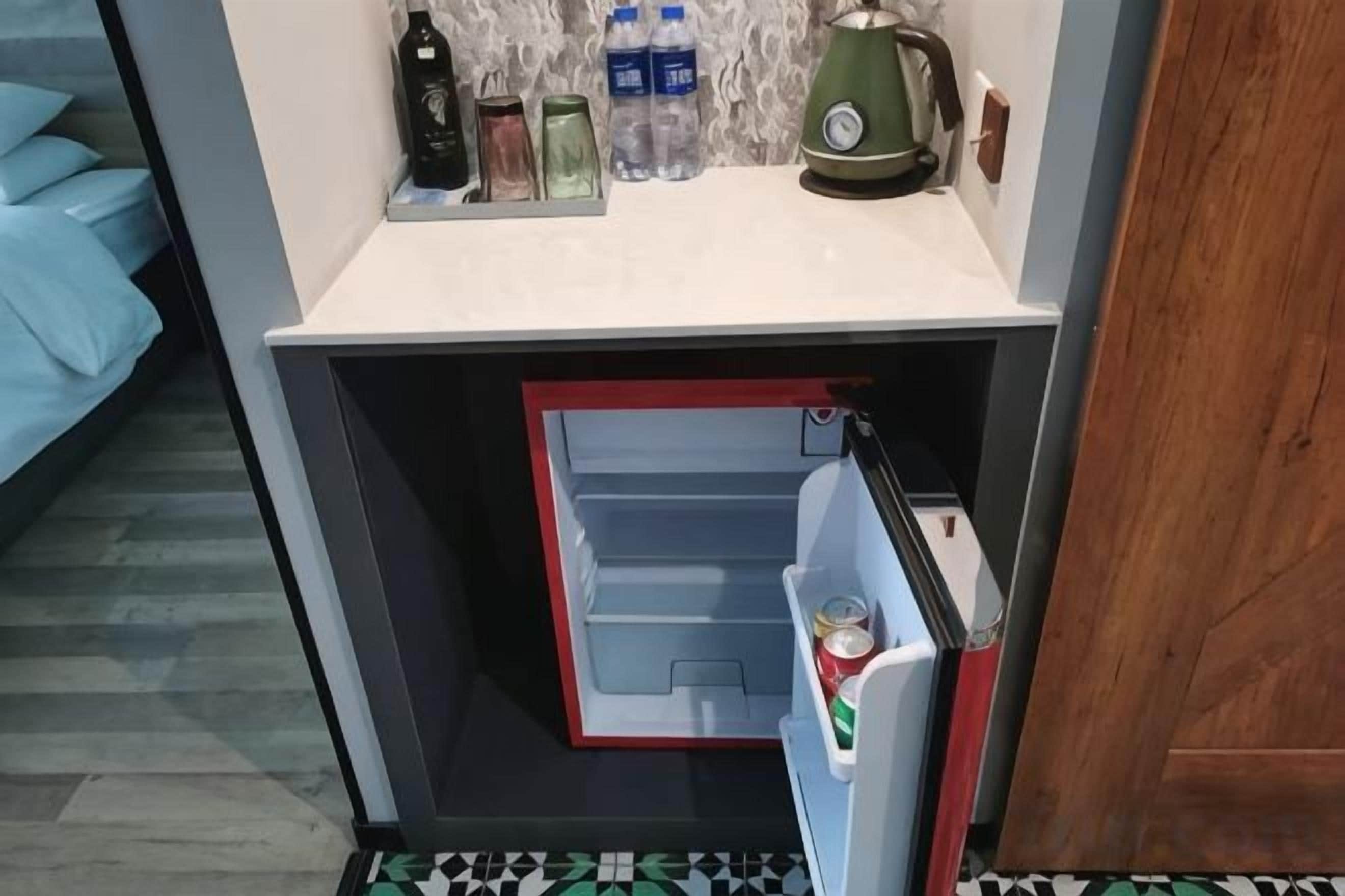 Una kitchenette compacta con refrigerador, microondas y una pequeña encimera.