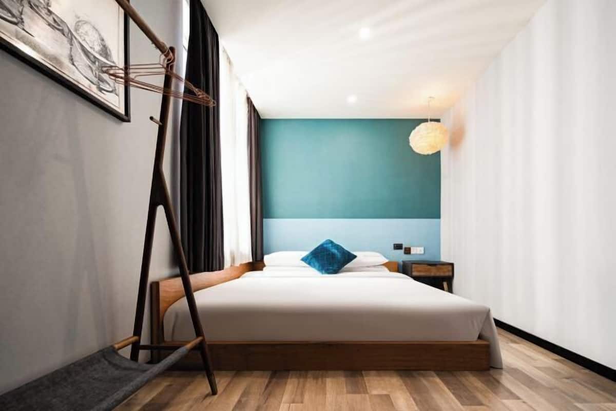Ein modernes Schlafzimmer mit einem Bett, einem Nachttisch, einer Hängeleuchte und einem Fenster mit Vorhängen.