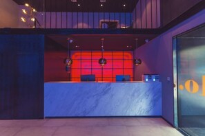 A reception area with a marble counter, two chairs, and a glass wall with a reflection. - Punk Ballet Ins Hotel (Zhenjiang)