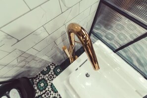 A bathroom with a white sink, a gold faucet, and a patterned floor. - Punk Ballet Ins Hotel (Zhenjiang)