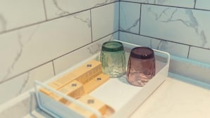 Una encimera de cocina con una bandeja blanca que contiene un tarro de vidrio verde, un tarro de vidrio marrón y una caja amarilla.