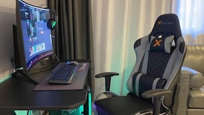 Una silla gamer, un escritorio con teclado y un monitor mostrando un videojuego.