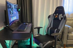 A gaming chair, a desk with a keyboard, and a monitor displaying a video game. - Punk Ballet Ins Hotel (Zhenjiang)