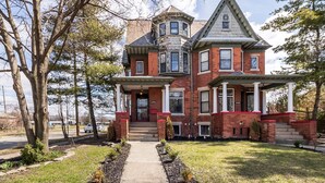 A large, two-story brick house with a prominent tower and bay windows, surrounded by a well-maintained lawn and trees. - Home Detroit Beautiful Historic  (Detroit)