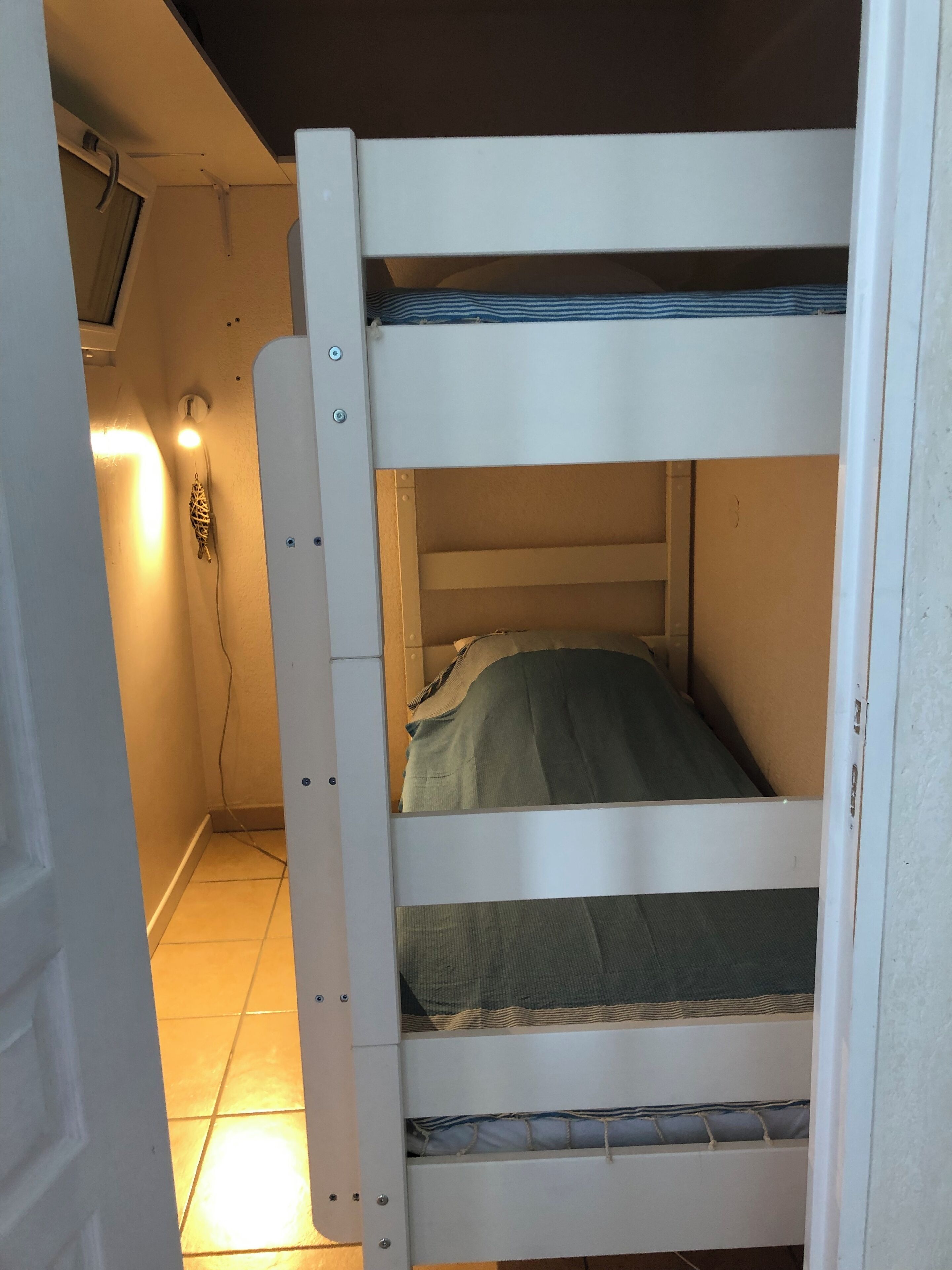 A bunk bed with a lower bunk and a mattress with a striped pillow.