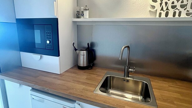 A modern kitchen with a Bosch dishwasher, a stainless steel sink, and a coffee maker.