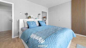 A modern bedroom with a bed, a bedside table, a wall-mounted shelf, and a wooden slat wall panel.
