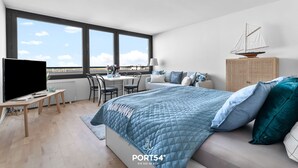 Ein modernes Schlafzimmer mit einem großen Bett, einem Schreibtisch und einer Segelboot-Dekoration.