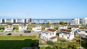 Ein Küstenwohngebiet mit modernen Häusern, einer Marina und blauem Himmel.