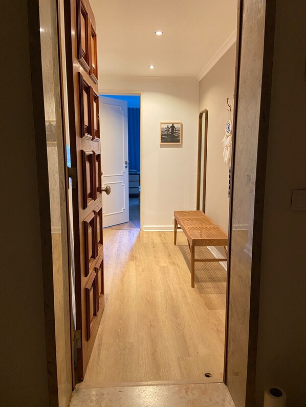 A hallway with a wooden door, a bench, and a framed picture on the wall. - Peaceful 2 bd with ocean view in Monte Estoril (Estoril)
