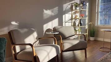 Un salon moderne avec deux fauteuils, une petite table ronde et une bibliothèque.
