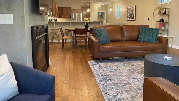 A modern living room with a brown leather sofa, a blue armchair, and a patterned rug. - Modern Luxury | Steps to Brady St (Milwaukee)