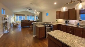 A spacious kitchen with granite countertops, wooden cabinets, and a central island. - Modern Luxury | Steps to Brady St (Milwaukee)