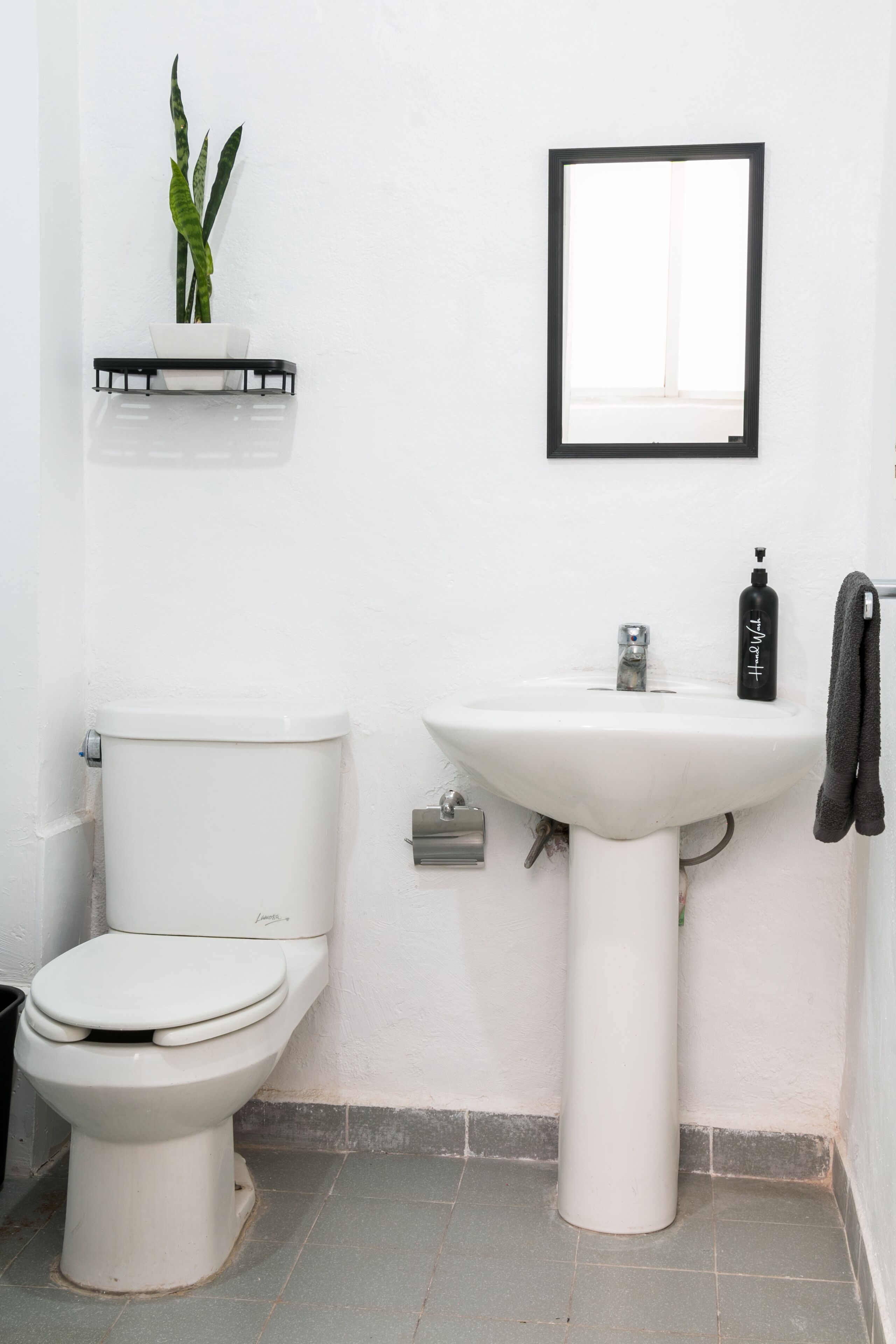 A bathroom with a toilet, sink, and a mirror.
