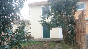 Un étroit sentier de pierres mène à un bâtiment doté d’une porte verte.