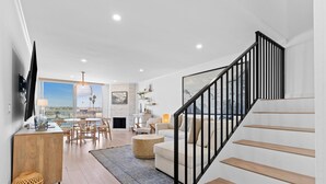 Ein modernes Wohnzimmer mit Treppe, Essbereich und Blick auf die Stadt.