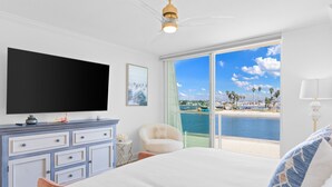 Ein Schlafzimmer mit einem großen Bett, einem Flachbildfernseher, einer Kommode und Meerblick.