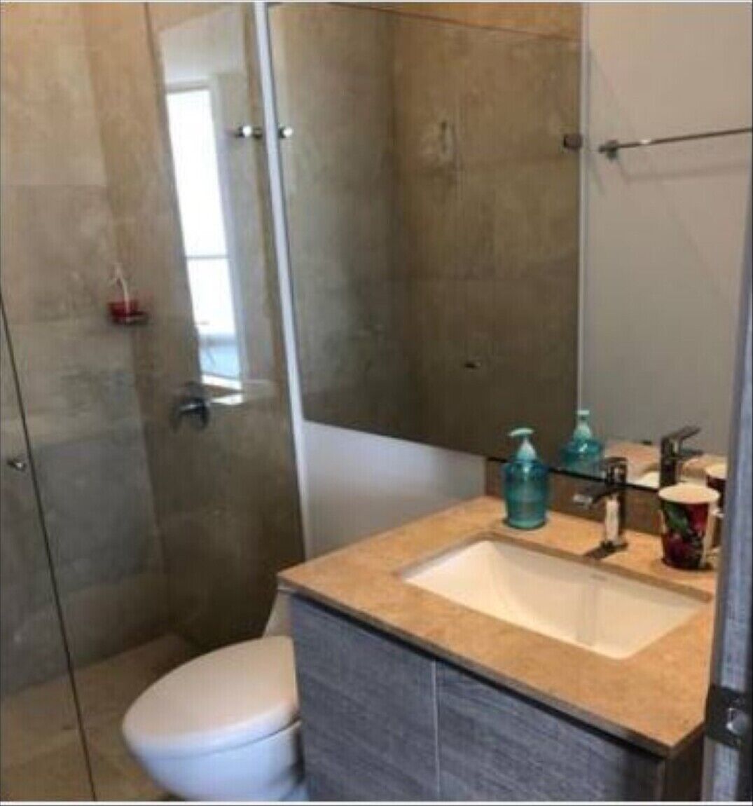 Un bagno moderno con box doccia in vetro, un WC bianco e un mobile da bagno color beige con lavandino e specchio.