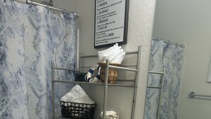 Une salle de bain avec un mur aux motifs de marbre, un lavabo blanc, des toilettes et un porte-serviettes avec des serviettes pliées.