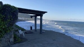 Une vue sur la côte, avec un mur de pierre, un espace de repos abrité et l’océan.