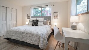A bedroom with a bed, bedside tables, a desk, and a window with curtains.