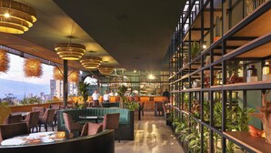 Un restaurante moderno con área de bar, asientos y plantas de interior.