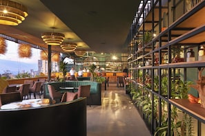 A modern restaurant with a bar area, seating, and indoor plants.